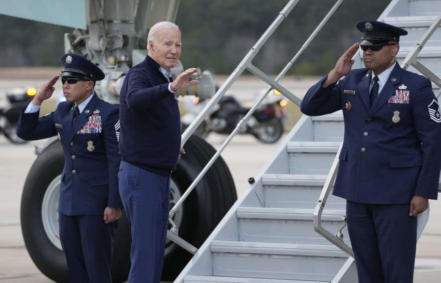 Joe Biden preparing to board a plane. He is waving to the camera.
